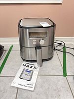 Front view of Kalorik MAXX Plus air fryer showing digital display, control dial and attached power cord