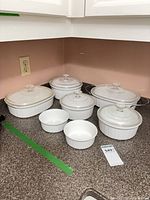 Group shot of all CorningWare dishes, lids and stand on countertop