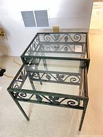 Three wrought iron frame glass nesting tables nested together