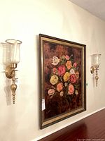 Pair of brass-tone wall sconces flanking painting on wall