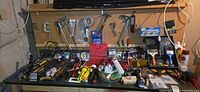 Workbench top with assorted tools, flashlights, painting supplies