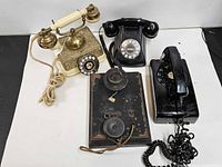Group shot of four telephones including Holtzer-Cabot wall unit, French-style ivory phone, Bell System rotary phone and Conair Metropolis phone