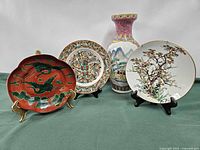 Front view of all four items: tall vase, three decorative plates on stands