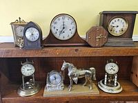 All eight clocks displayed on two-tier wooden shelf