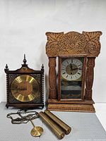 Both clocks side by side with weights and pendulum visible