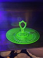 Server glowing bright green under UV, showing floral pattern and handle