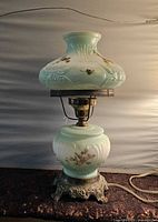 Full view of hurricane lamp showing shade, font, metal base, and cord