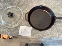 Skillet and lid displayed on countertop with size reference