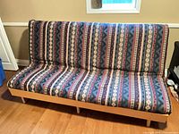 Front view of futon in sofa position displaying upholstery pattern and wooden base