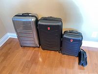 Three suitcases and toiletry bag lined up showing relative sizes and condition