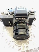 Front view of Minolta XE-5 SLR with attached Minolta lens and body cap