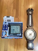 Boxed La Crosse wireless forecast station alongside wall barometer