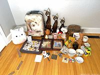 Wide shot of entire lot on floor showing suitcase, statues, stool, mugs, bowls, framed art, fabric mat and various small items