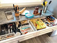 Open drawers showing flatware, utensils, trays, and countertop tools
