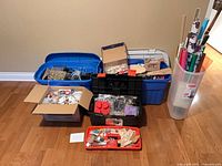 Five packed containers with assorted craft items and wrapping paper rolls