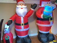 Three inflated decorations: Snoopy doghouse, mid-size Santa, large Santa with present