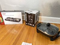 Overall view showing boxed Master Chef double burner, boxed Proctor Silex coffee maker, and unbranded electric skillet