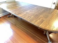 Table fully extended with leaves installed showing top surface wood grain and wear