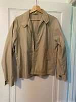 Full view of beige zip-front jacket on hanger