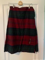 Full view of front of kilt showing tartan pattern and pin