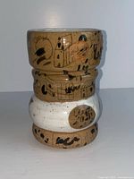 front view of tan and white ceramic vase with black abstract painting