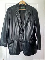 Front view of black leather Danier blazer jacket on hanger showing buttons, pockets, lapels