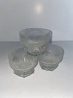 Three clear textured glass dessert bowls stacked to show exterior pattern and faceted bases