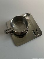 cup on saucer with spoon angled view showing finish and integrated handle