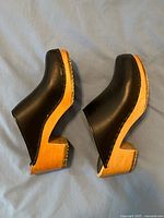 Side profile of both clogs showing leather uppers and wood soles