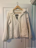 Full frontal view of white windbreaker on hanger