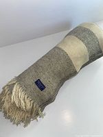 Rolled grey and off-white wool blanket on white surface