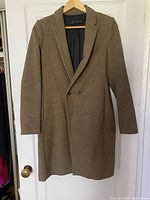 Full front view of brown long coat hanging on door