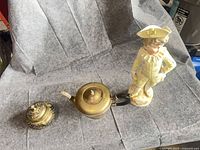 All three items—porcelain figurine, brass container, E.P. copper teapot—group shot