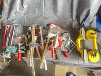 Overview of bar clamps, C-clamps, caulking guns, suction lifter on felt surface