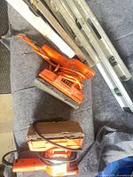 Overview of two orange sanders and stack of aluminum levels