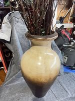 Full view of cream to brown ceramic vase with artificial branches