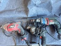 Three corded electric drills laid out side by side