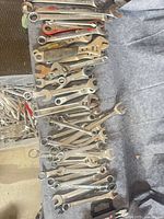 Top-down view of wrenches laid out on grey surface, showing mix of combination, box-end and adjustable wrenches