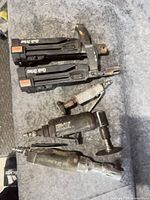 All five pneumatic items laid out: two Quik Drive attachments, die grinder, rotary cutter, air ratchet