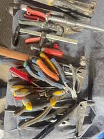 Assorted screwdrivers, pliers, C-clamp, aviation snips, hammer and stapler visible