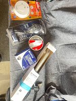 All packaged items laid out: grab bar, shower head, smoke alarm, drains, Husky snips