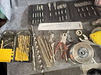 assorted drill bits, pliers and grinding disc on surface