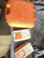 Closed orange Paslode Impulse case with two Paslode nail boxes