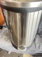 Front view of stainless-steel pedal trash can showing foot pedal and cylindrical body