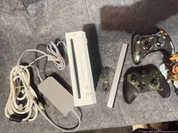 Overall view showing Wii console, power brick, cables, sensor bar and two Xbox 360 controllers