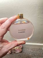 Front view of round Chanel Chance Eau Tendre bottle held in hand