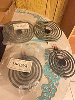 Four stove coils, two labeled MP21YA and two labeled MP15YA