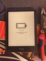Front view showing screen with low battery icon and Kindle logo