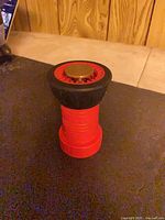 Front view of red hose nozzle showing brass tip and black rubber bumper