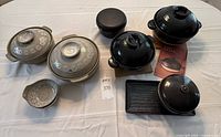 Overview of all earthenware pieces on table: six lidded pots, two bowls, tray